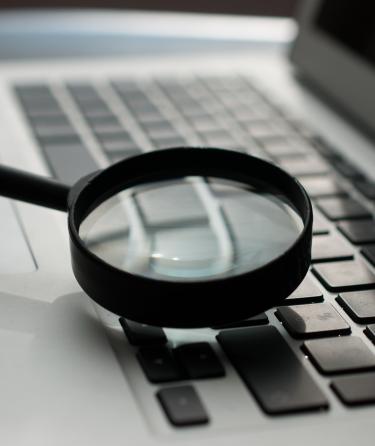 A magnifying glass being held to a laptop's keyboard. Source: https://unsplash.com/photos/d9ILr-dbEdg