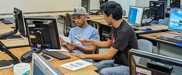 LAMC representative assisting a student at a computer to enroll in classes
