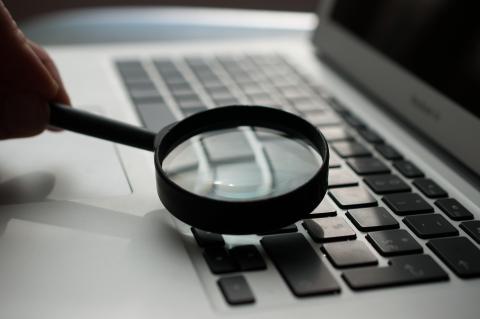 A magnifying glass being held to a laptop's keyboard. Source: https://unsplash.com/photos/d9ILr-dbEdg